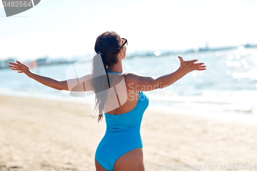 Image of young woman in swimsuit posing on beach