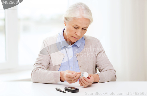 Image of senior woman with glucometer checking blood sugar