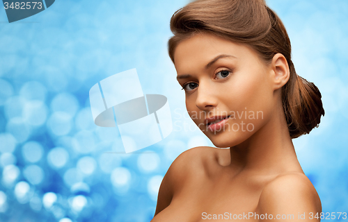 Image of woman with bare shoulders over blue lights