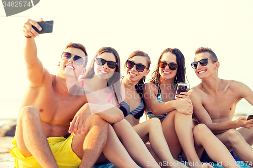 Image of friends with smartphones on beach