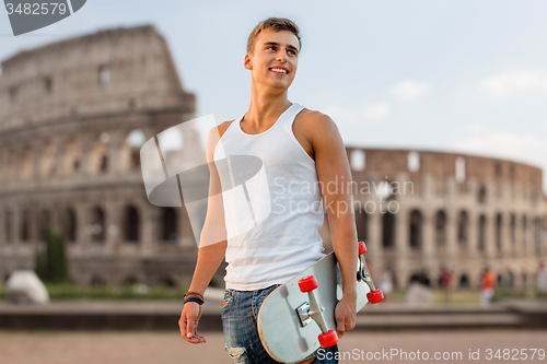 Image of smiling teenage boy with skateboard over coliseum