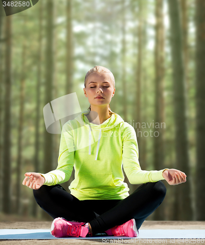 Image of happy young woman doing yoga outdoors