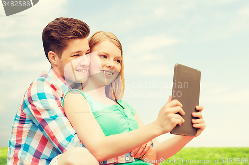 Image of happy couple with tablet pc taking selfie outdoors