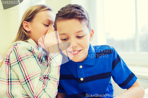 Image of smiling schoolgirl whispering to classmate ear