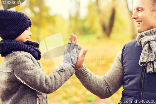 Image of happy father and son making high five in park