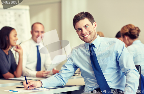 Image of group of smiling businesspeople meeting in office