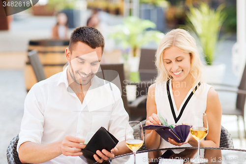 Image of happy couple with wallet paying bill at restaurant