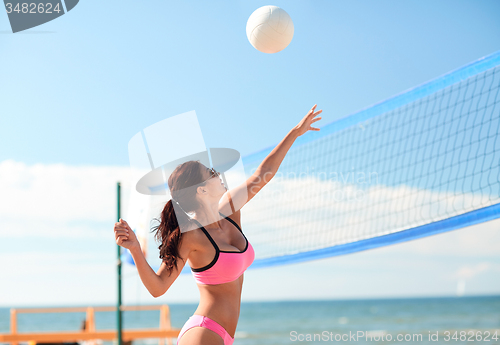 Image of young woman with ball playing volleyball on beach