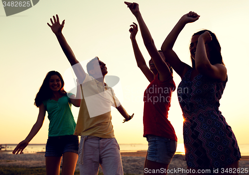 Image of smiling friends dancing on summer beach