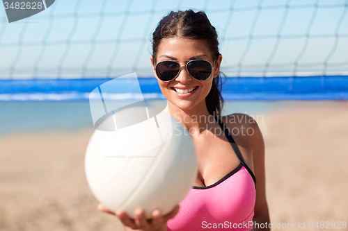 Image of young woman with volleyball ball and net on beach