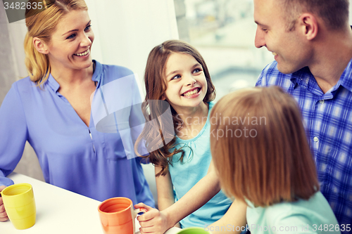 Image of happy family drinking tea with cups at home