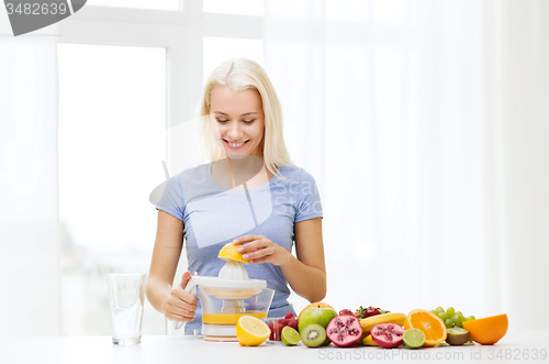 Image of smiling woman squeezing fruit juice at home