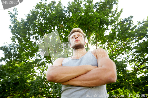 Image of sporty young man with crossed arms at summer park