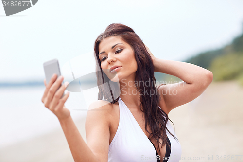 Image of young woman taking selfie with smartphone