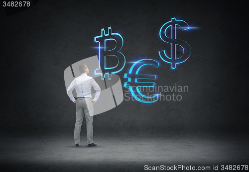 Image of businessman looking at currency symbols