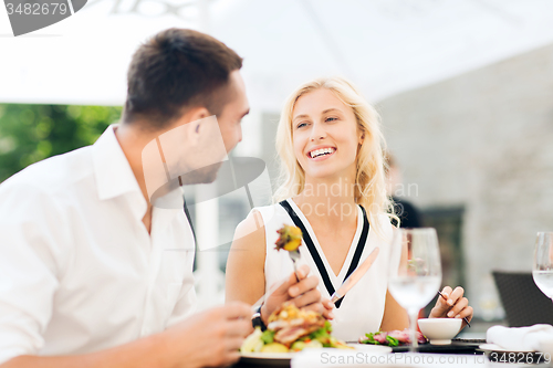 Image of happy couple eating dinner at restaurant terrace