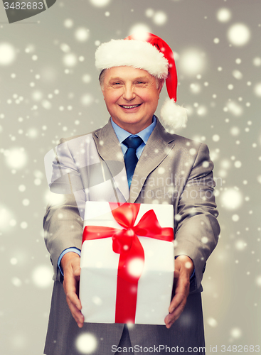 Image of smiling man in suit and santa helper hat with gift