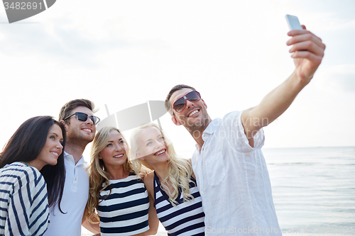 Image of happy friends on beach and taking selfie