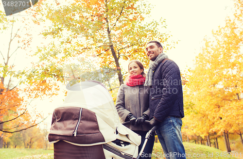 Image of smiling couple with baby pram in autumn park