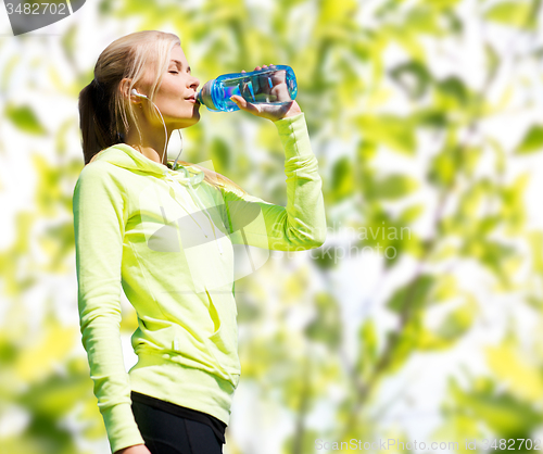 Image of woman drinking water after doing sports outdoors