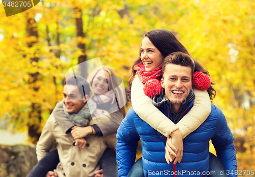 Image of smiling friends having fun in autumn park