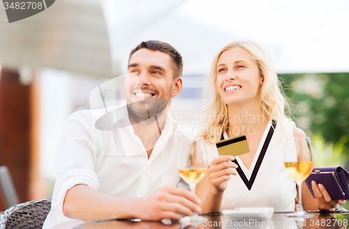 Image of happy couple with bank card and bill at restaurant