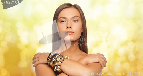 Image of beautiful woman with bracelets over yellow lights