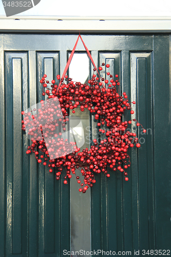 Image of Berry christmas wreath with decorations on a door