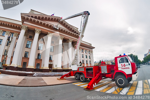 Image of Builders paint building facade by fire truck