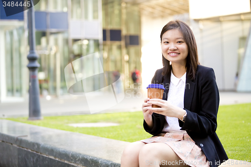 Image of Young female Asian executive drinking coffee