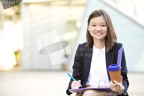 Image of Young female Asian business executive holding file