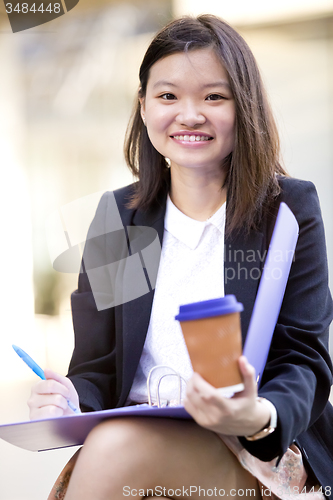 Image of Young female Asian business executive holding file