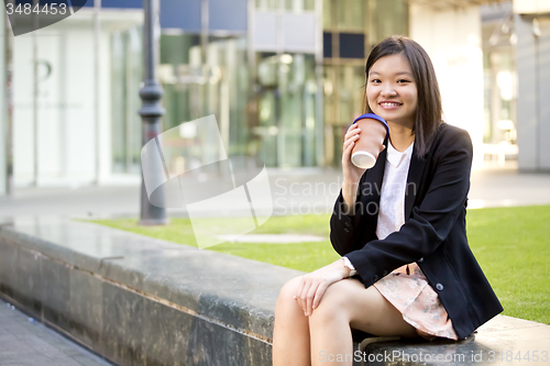 Image of Young female Asian executive drinking coffee