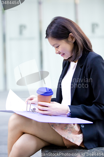 Image of Young female Asian business executive holding file