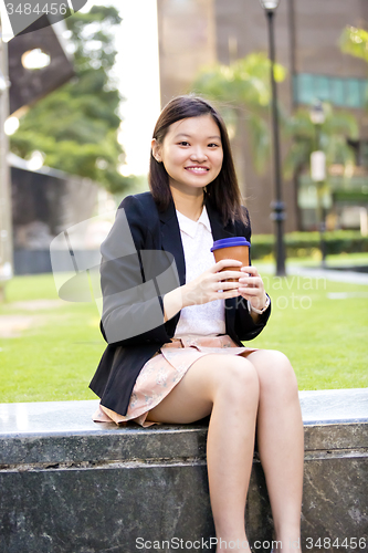 Image of Young female Asian executive drinking coffee
