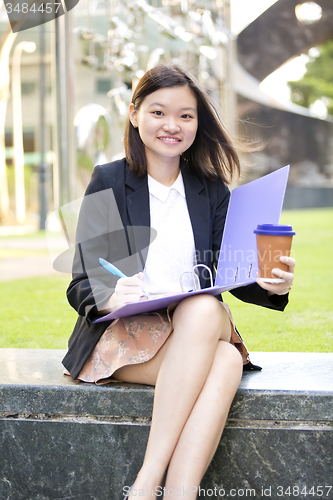 Image of Young female Asian business executive holding file