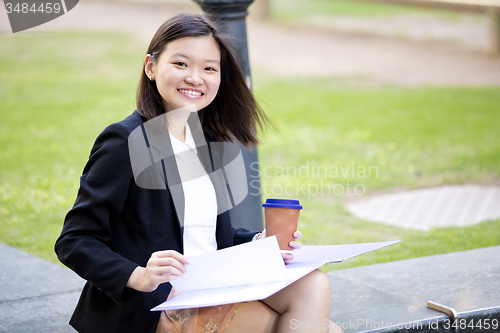 Image of Young female Asian business executive holding file