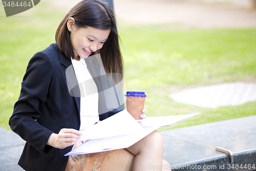 Image of Young female Asian business executive holding file