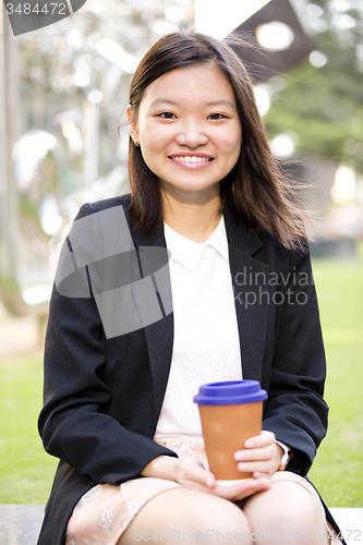 Image of Young female Asian executive drinking coffee
