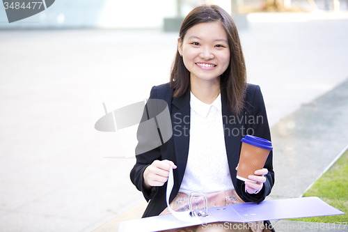 Image of Young female Asian business executive holding file