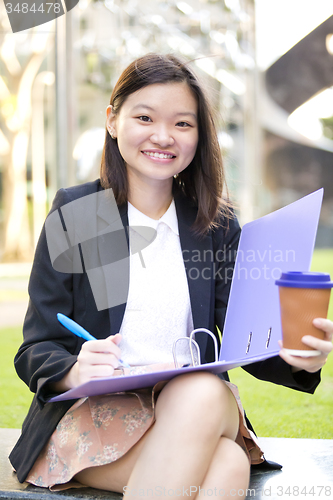 Image of Young female Asian business executive holding file