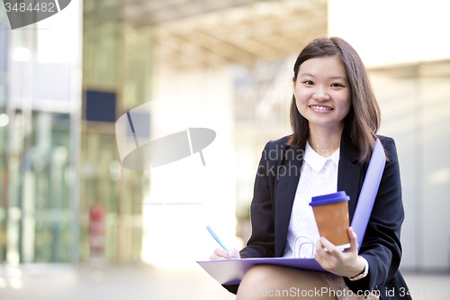 Image of Young female Asian business executive holding file