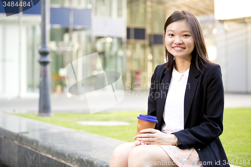 Image of Young female Asian executive drinking coffee