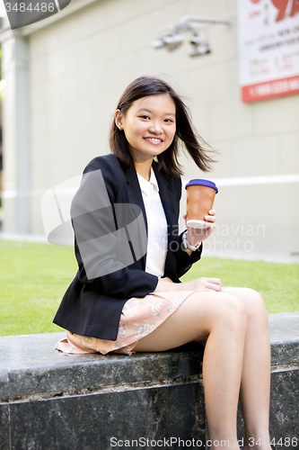 Image of Young female Asian executive drinking coffee