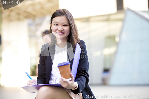 Image of Young female Asian business executive holding file