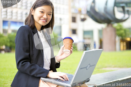 Image of Young Asian female business executive using laptop