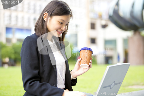 Image of Young Asian female business executive using laptop