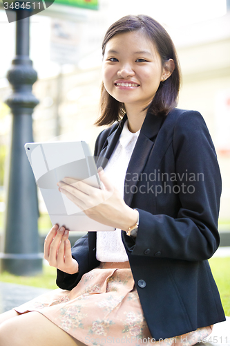 Image of Young Asian female business executive using tablet