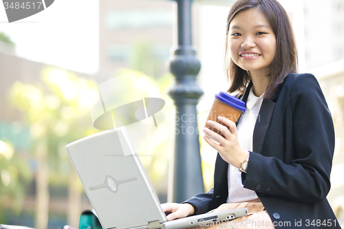 Image of Young Asian female business executive using laptop