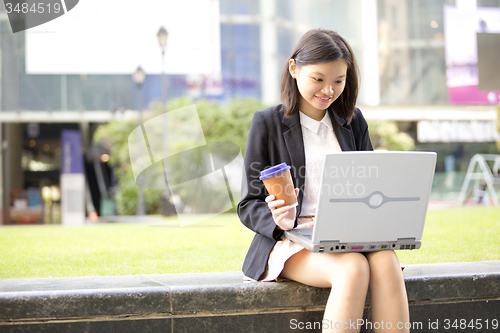 Image of Young Asian female business executive using laptop